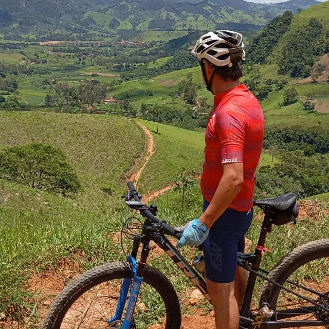 Ciclista com mountain bike numa trilha de terra, com o vale ao fundo